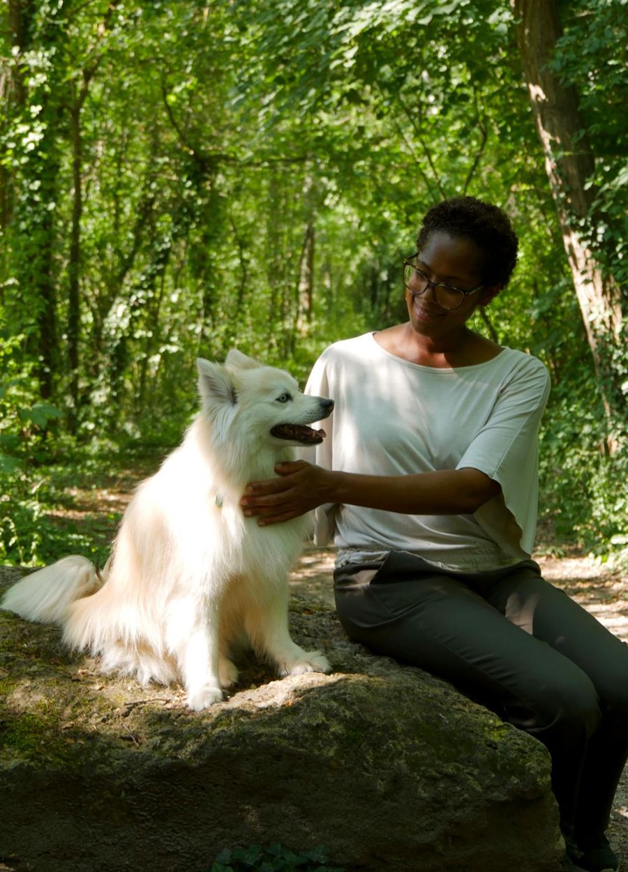 Elmina caresse son chien blanc en forêt